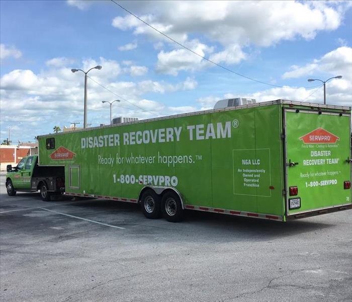 Our green Disaster Recovery Truck parked outside of a large commercial building.